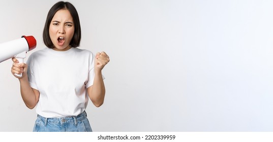 Angry Asian Girl Activist, Holding Megaphone And Looking Furious, Protesting, Standing Over White Background