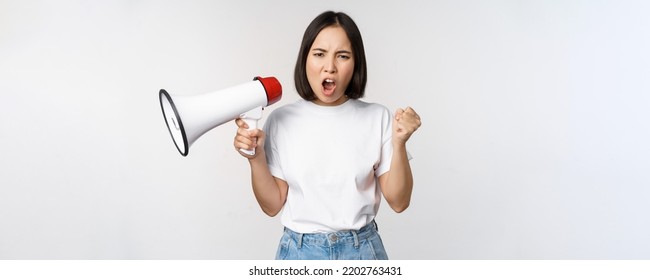 Angry Asian Girl Activist, Holding Megaphone And Looking Furious, Protesting, Standing Over White Background