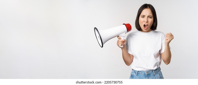 Angry Asian Girl Activist, Holding Megaphone And Looking Furious, Protesting, Standing Over White Background