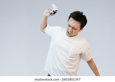angry asian man throwing controller in studio background
