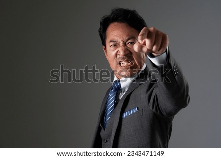 Angry Asian middle aged businessman in black background
