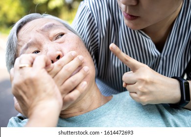 Angry asian woman covering senior mouth and showing silence gesture, keep a secret be quiet,social violence,aggression, scared elderly people with female caregiver,bad relationship,physical abuse
