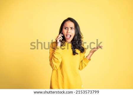 angry asian woman making a call using a cell phone on isolated background