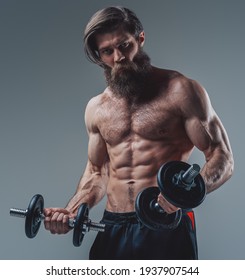 Angry athlete with muscular and naked body holding dumbells