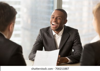 Angry bad african american boss yelling at caucasian employees, receiving reprimand with guilty and shocked expressions, showing authority, pointing at male worker made mistake, scolding for failure