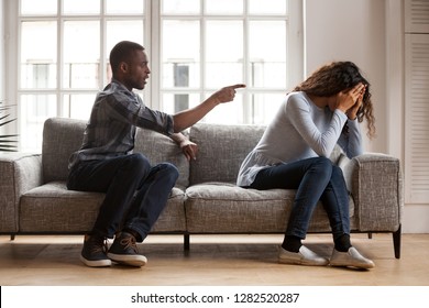 Angry black husband arguing yelling blaming upset wife of problems, jealous distrustful dominant african american boyfriend controlling shouting at sad girlfriend, quarrelling family fight at home