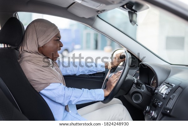 Angry Black Muslim Businesswoman Driving Car, Stuck\
In Traffic, Having Accident, Beeping Horn, Stressed Female Driver\
Screaming At Somebody, Emotionally Reacting To Road Jam, Side View,\
Free Space