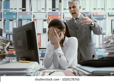 Angry boss yelling at his young employee, she is stressed and feeling frustrated: bullying boss and mobbing concept