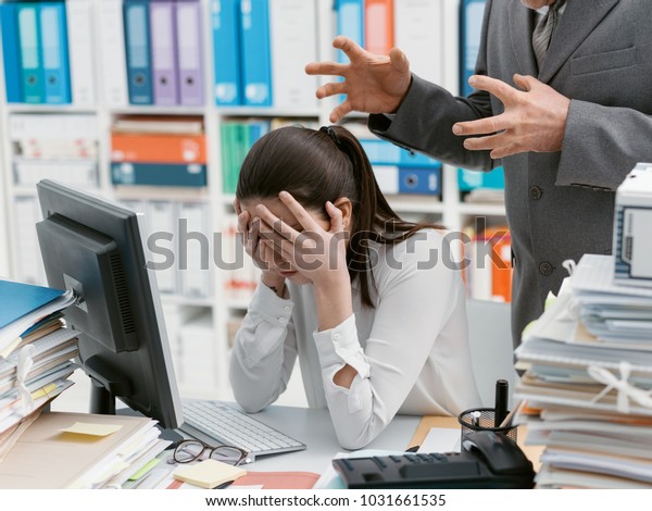 Angry boss\
yelling at his young employee, she is stressed and feeling\
frustrated: hostile boss and mobbing\
concept