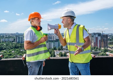 Angry boss yelling in megaphone at his builder because he made mistake on construction on the urban background - Powered by Shutterstock