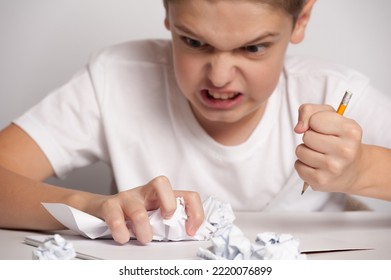 angry boy emotionally tearing a page from a notebook showing rage - Shutterstock ID 2220076899