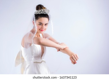 Angry Bride. Beautiful, Pretty, Furious Woman In Wedding Dress Girl, Bride, Lady Shows Her Hand With A Fist On A Gray Background. Copy Space