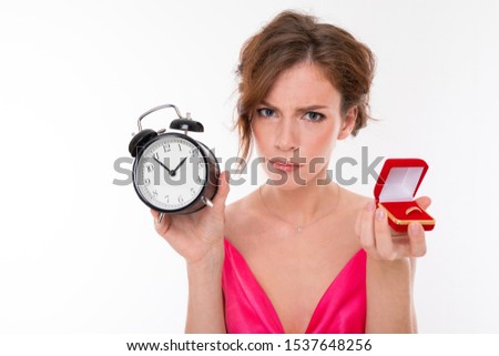 angry bride on a white background with a wedding ring in her hands, a girl hints to the groom about the wedding