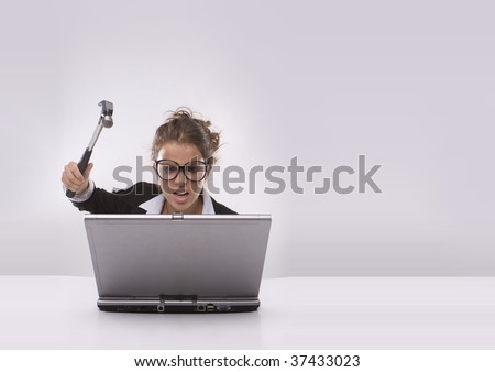  Angry brunette businesswoman with hammer and glasses against laptop