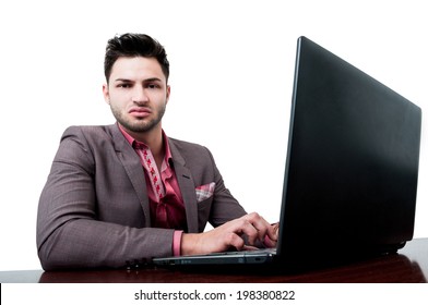 Angry Business Man With Dark Hair Looking At The Camera While Typing On His Laptop And Sitting At The Desk