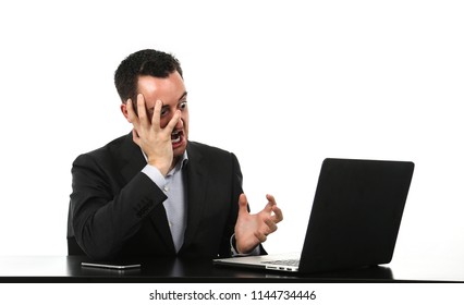 Angry business man stressed at his desk in front of his laptop against a white background - Shutterstock ID 1144734446
