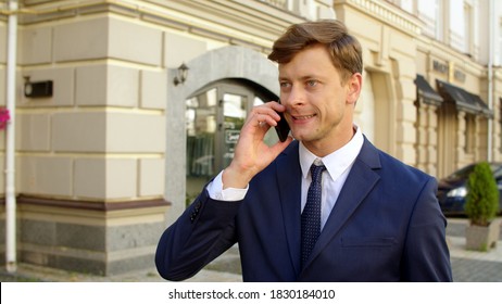 Angry Business Man Talking Mobile Phone Outdoors. Serious Businessman Walking With Cellphone Outside In Slow Motion. Focused Professional Call Phone On The Go At City Street.