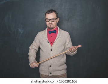 Angry business man or teacher with pointer on blackboard background - Shutterstock ID 1636281106