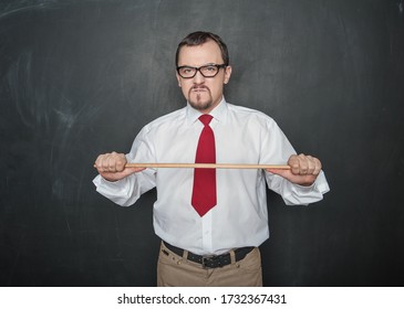 Angry business man or teacher with pointer on blackboard background - Shutterstock ID 1732367431