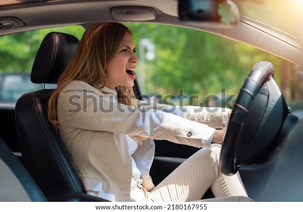 Angry business woman honking in her car\
while driving. Angry woman driving a\
car