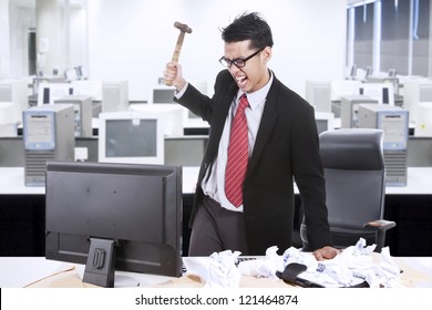 Angry Businessman Is About To Throw A Hammer At His Computer In The Office