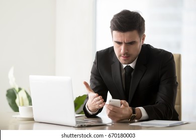 Angry Businessman Annoyed With Phone Call While Working On Laptop At Office, Receiving Bad News On Smartphone, Irritated By Spamming Message, Mobile Not Working, Battery Needs Recharge, Broken Cell 