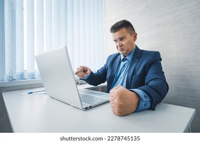 angry businessman in a jacket slams his fist on the table in anger. the Internet or computer does not work bad news, bankruptcy.