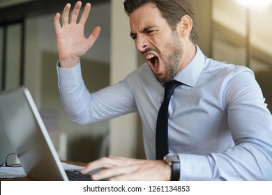 Angry Businessman Losing Patience And Screaming At Laptop In Modern Office