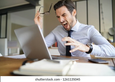 Angry Businessman Losing Patience And Screaming At Laptop In Modern Office