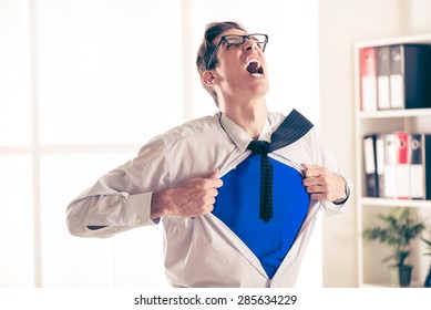 Angry Businessman Ripping Open His Shirt And Exposing A Superhero Red Costume Underneath. The Man Is Wearing Glasses.