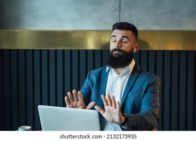 Angry Businessman Talking On Video Call Meeting With Colleagues On His Laptop Computer From A Restaurant.
 
Serious Business Man With Beard Showing Stop Sign To Laptop Screen At Online Web Conference.