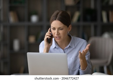 Angry businesswoman talking on phone, looking at laptop screen, irritated young woman arguing with customer client, having unpleasant conversation, holding smartphone, solving business problem - Powered by Shutterstock