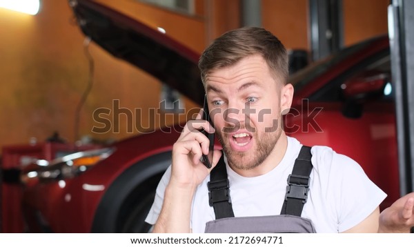 An angry car mechanic\
is talking on a smartphone, he is shouting loudly into the phone.\
Car mechanic