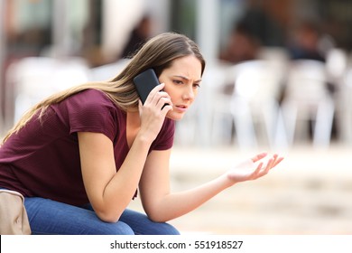 Angry Casual Woman Calling On The Phone Sitting On A Bench In The Street