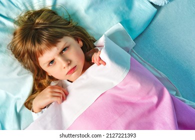 Angry Child Girl Lying On The Bed Covered Blanket And Refuses To Sleep