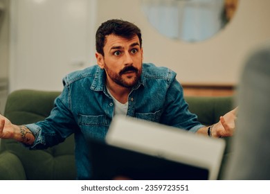 An angry client is having a severe conversation with a shrink in the office during his session. A furious man is expressing anger and disappointment during his session with a psychotherapist.