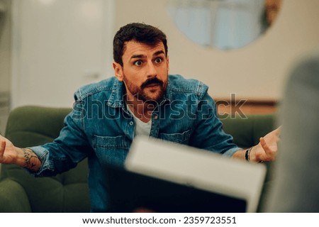 An angry client is having a severe conversation with a shrink in the office during his session. A furious man is expressing anger and disappointment during his session with a psychotherapist.