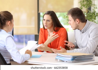 Wütende Ehepaare, die ihre Probleme erklären wollen, indem sie auf einem Schreibtisch einer Heiratsberatung oder eines Büros sitzen