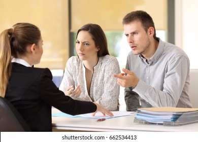 Angry couple claiming to a businesswoman at office