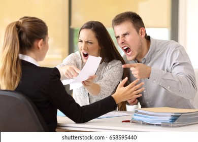 Angry couple claiming and shouting to an office worker  - Shutterstock ID 658595440