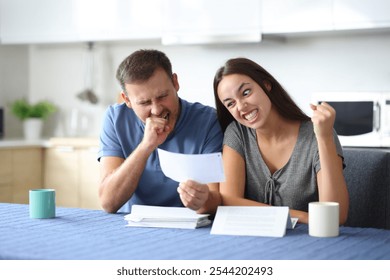 Angry couple having problem checking bills in the kitchen at home