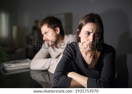 Angry couple ignoring each other sitting in the living room at home in the night