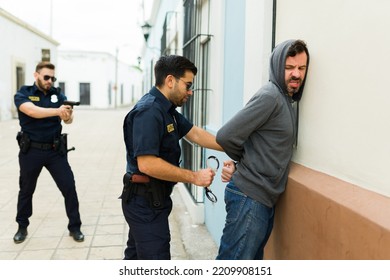 Angry Criminal Robber Resisting Arrest And A Cop Putting Handcuffs After Detention For Committing Crime