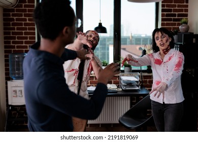 Angry Cruel Zombies Chasing Frightened Man In Business Office, Looking Dangerous And Creepy. Spooky Evil Monsters Attacking Person To Kill, Having Bloody Scars And Wounds, Being Aggressive.