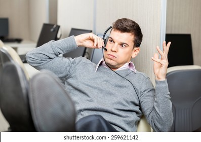 Angry Customer Service Representative Gesturing While Using Headset In Office