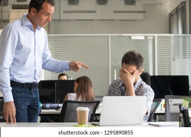 Angry dissatisfied boss ceo scolding employee in office. Frustrated office worker sitting at desk cover face with hand feels upset, director dismisses man for low poor result asking to leave workplace