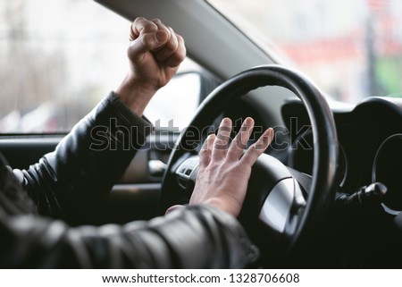 Angry driver is honking and is yelling by sitting of a steering wheel. Road aggression concept. Traffic jam. 商業照片 © 