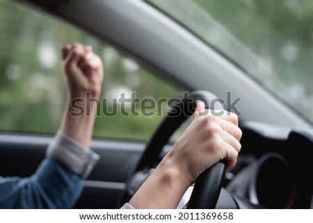 Angry driver shakes her fist in the traffic jam.