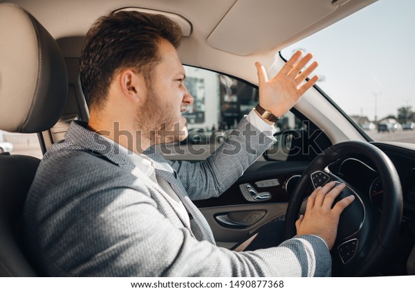 Angry driver in a traffic jam loosing\
his tamper and gesturing to let his car go. Being\
late