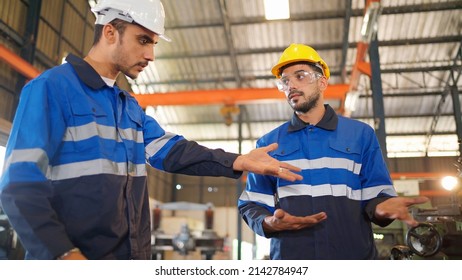 Angry Engineer Boss Scolding Young Engineers For Their Mistake Standing In The CNC Manufacturing Factory. Negative Boss Yelling Employee During Work. Man Standing And Feeling Bad. Industrial Concept